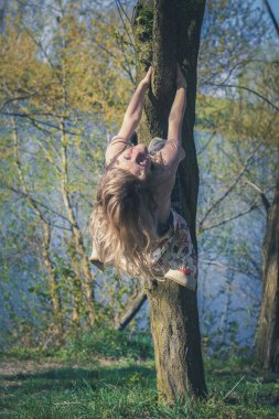 happy girl climbing up the tree in vivid green spring nature