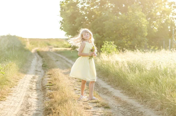 夏の雰囲気の田舎道に長いブロンドの髪のかわいい女の子 — ストック写真