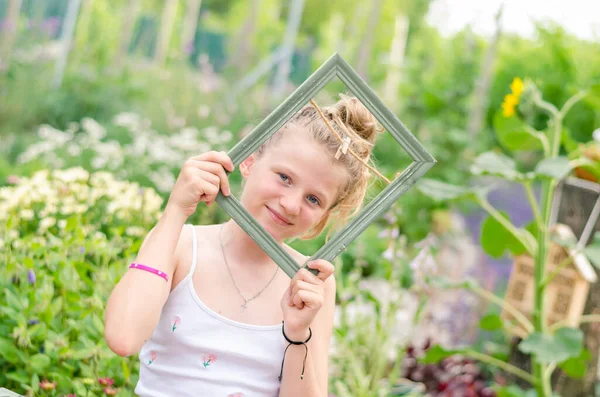 Schöne Lächelnde Blonde Mädchen Mit Rahmen Der Hand Grünen Garten — Stockfoto