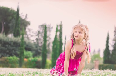 Küçük çocuk yeşil çayırda poz veriyor.