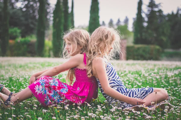 2人のブロンドの女の子イタリア トスカーナ州の日当たりの良い牧草地でリラックス ロイヤリティフリーのストック写真