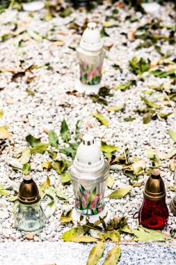 Mezarlıktaki mezarda mum yakmak ve dekoratif kasımpatı çiçekleri yakmak.