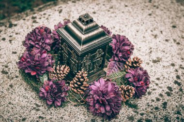 Yanan mumlu dekoratif fener, mezarlıktaki mezardaki çiçekler.