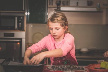 Çocuklar mutfakta zencefilli ekmek hazırlıyor, festival havası var.