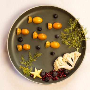 Domates, nar ve karnabahardan gelen balıklı çocuklar için yaratıcı tabak, sihirli deniz dünyası