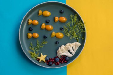 Domates, nar ve karnabahardan gelen balıklı çocuklar için yaratıcı tabak, izole edilmiş büyülü deniz dünyası.