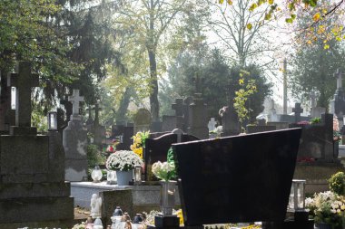 Mezarlıkta süslü mezarlar ve mezarlar, kasımpatı çiçekleri, haçlar ve mumlar.