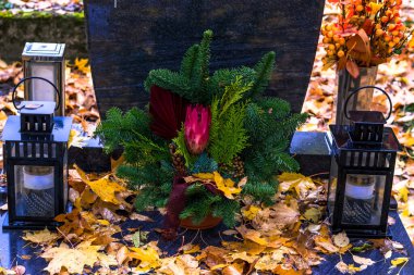 Fenerlerle süslenmiş mezarlar, yanan mumlar, renkli kasımpatı çiçekleri, katolik semboller.