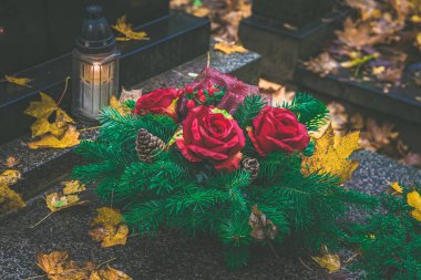 Fenerlerle süslenmiş mezarlar, yanan mumlar, renkli kasımpatı çiçekleri, katolik semboller.