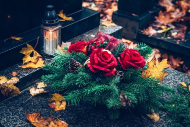 Fenerlerle süslenmiş mezarlar, yanan mumlar, renkli kasımpatı çiçekleri, katolik semboller.