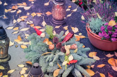 Fenerlerle süslenmiş mezarlar, yanan mumlar, renkli kasımpatı çiçekleri, katolik semboller.