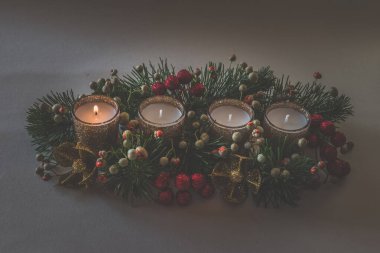 Dört beyaz mum, çiçekli çelenk süslemesi, izole edilmiş, yanan bir mum.