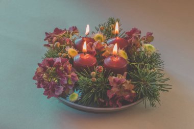 Dört beyaz mum, çiçekli çelenk süslemesi, izole edilmiş, yanan dört mum.