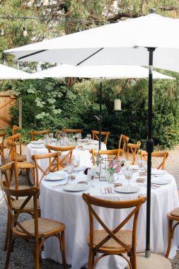 Arka bahçe düğün resepsiyonu - beyaz masa örtülü yuvarlak masalar, klasik fenerler, güller ve sümbül sandalyeler,