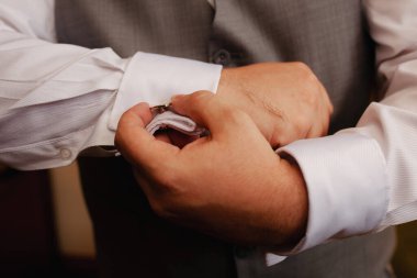 CLose up of  man putting on a cuffling on white dress shirt.