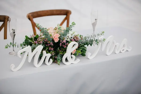 Sweethearts table close up - white tablecloth with rustic floral attangement, champagne flutes and Mr & Mrs sign