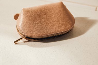 Bej renkli kozmetik çanta, beyaz mermer kaplama, nemli alan.