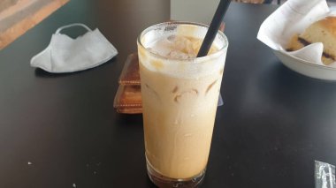 Arzularınızı ferahlatıcı bir bardak çikolatayla giderin. Buz küpleriyle süslenmiş, parlak, siyah bir masaya kurulmuş.