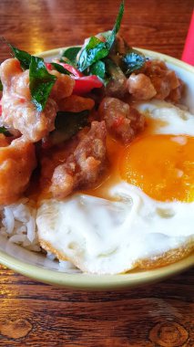 Kırsal bir ahşap masada servis edilen yumurta, tavuk ve baharatlı biber karışımıyla süslenmiş cazip bir tabak.