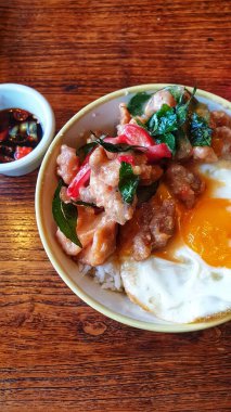 Kırsal bir ahşap masada servis edilen yumurta, tavuk ve baharatlı biber karışımıyla süslenmiş cazip bir tabak.