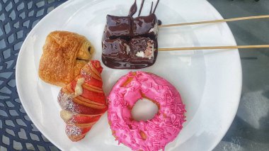 Lezzetli donut ve hamur işlerini beyaz bir tabağa güzelce yerleştirin, her durum için ağız sulandırıcı bir ikram.