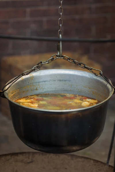 Cooking street food. Cooking soup in a cauldron on a fire outside. Outdoor kitchen