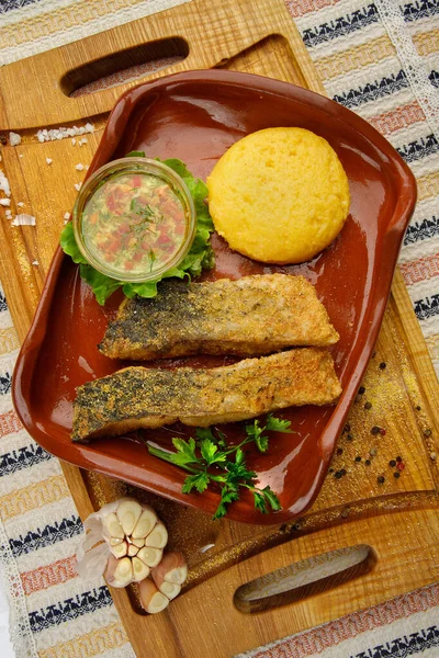 stock image Whole fried fish in a red plate served with mamaliga and garlic souce