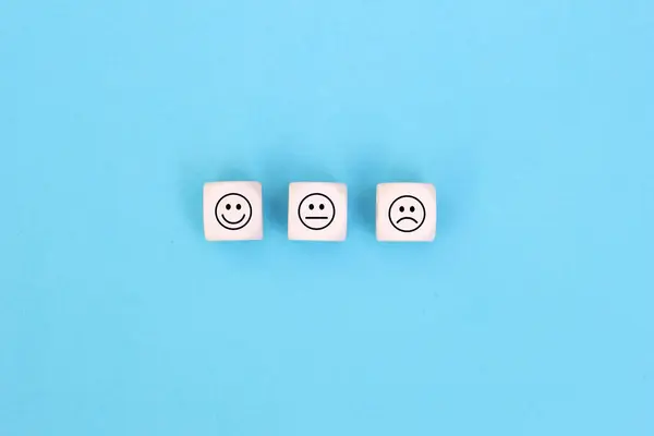 Happy sad and neutral smile faces on wooden blocks on Blue background. Customer satisfaction, evaluation or feedback concept.