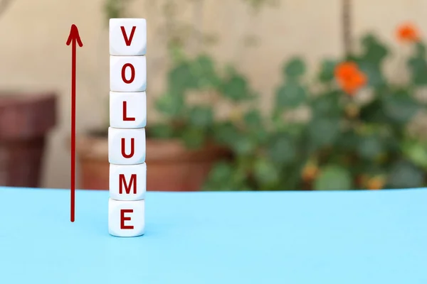The word volume on stacked cubes with arrow. Increasing music volume or production quantity or capacity in business concept.