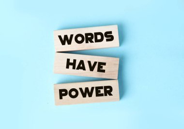 The phrase Words Have Power on wooden blocks laying on blue background. Copywriting advertising PR concept clipart