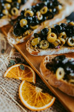 Parti için fırça seti, mantarlı, domatesli, parmesan peynirli, taze fesleğenli ve koyu arkaplanlı ahşap üzerine balzamik soslu küçük sandviçler.