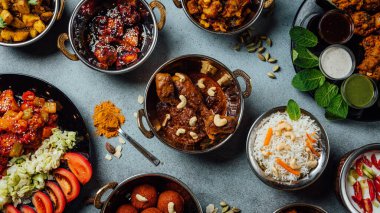 Assorted indian food on stone background. Dishes of indian cuisine. Curry, butter chicken, rice, lentils, chutney, spices. Space for text. Bowls and plates with indian food