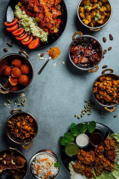 Vertical photo of sssorted indian food on stone background. Dishes of indian cuisine. Curry, butter chicken, rice, lentils, chutney, spices. Space for text. Bowls and plates with indian food