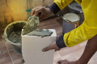 İnşaat ustası tuğla ustası mala ve çimento harcı ile tuğla işi yapıyor.