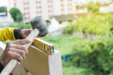 İnşaat ustası tuğla ustası mala ve çimento harcı ile tuğla işi yapıyor.