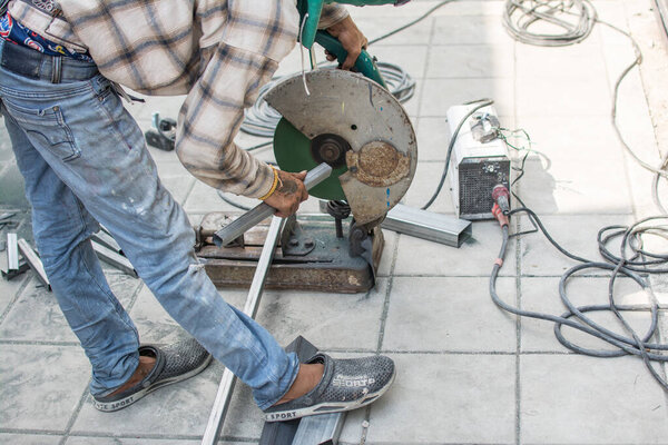 worker cuts a metal pipe with some electric device or appliance