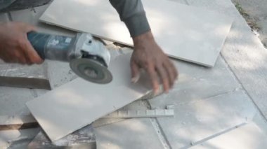 İnşaat alanındaki bir açı öğütücüyle fayans kesen bir işçi.