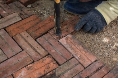 İşçi evin etrafına kırmızı tuğla döşemiş.