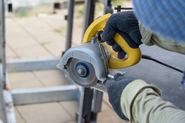 Kesilen çimento tahtası için öğütme makinesi kullanan işçiler.