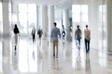 Bulanık bir geçmişi olan modern bir iş merkezinin lobisindeki insanların soyut görüntüleri.