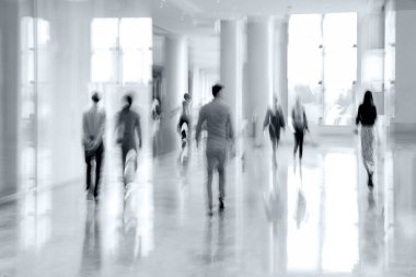 Bulanık bir geçmişi olan modern bir iş merkezinin lobisindeki insanların soyut görüntüleri.