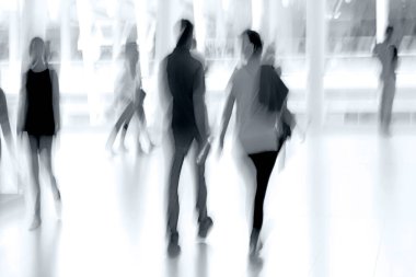 Bulanık bir geçmişi olan modern bir iş merkezinin lobisindeki insanların soyut görüntüleri.