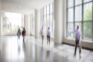 Bulanık bir geçmişi olan modern bir iş merkezinin lobisindeki insanların soyut görüntüleri.