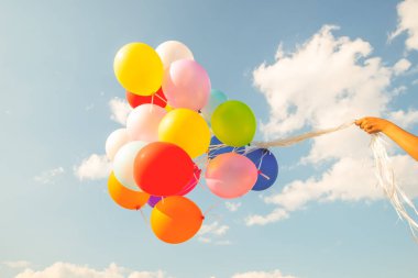 Hand holding multi colored balloons done with a retro vintage  filter effect. concept of festival, celebration, birthday, for background design.