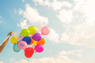 Hand holding multi colored balloons done with a retro vintage  filter effect. concept of festival, celebration, birthday, for background design.