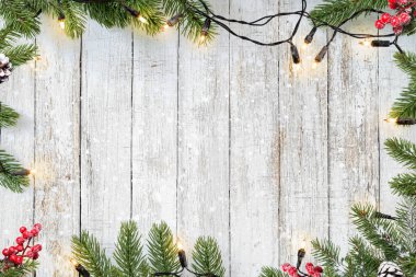 Noel arkaplanı. Ampul ve çam yaprakları beyaz tahta üzerinde Noel süslemesi yapar. Mutlu Noeller ve yeni yıl tatili geçmişi. üst görünüm çerçeve sınır tasarımı.