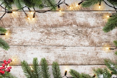 Noel arkaplanı. Ampul ve çam yaprakları beyaz tahta üzerinde Noel süslemesi yapar. Mutlu Noeller ve yeni yıl tatili geçmişi. üst görünüm çerçeve sınır tasarımı.