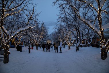 İnsanlar Aspen Colorado 'da ışıklandırılmış bir sokak sahnesinde soğuk bir kış akşamının tadını çıkarıyorlar.