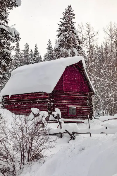 冬日的傍晚 红色的谷仓被白雪覆盖 雪花飘扬在空中 图库照片
