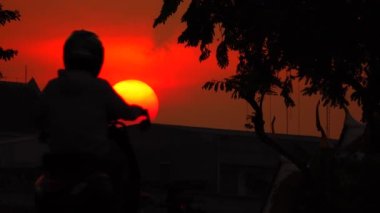 4K Günbatımı Gökyüzü sarı bulutlar mavi gökyüzü kedi motosikleti üzerinde şehir arka planında